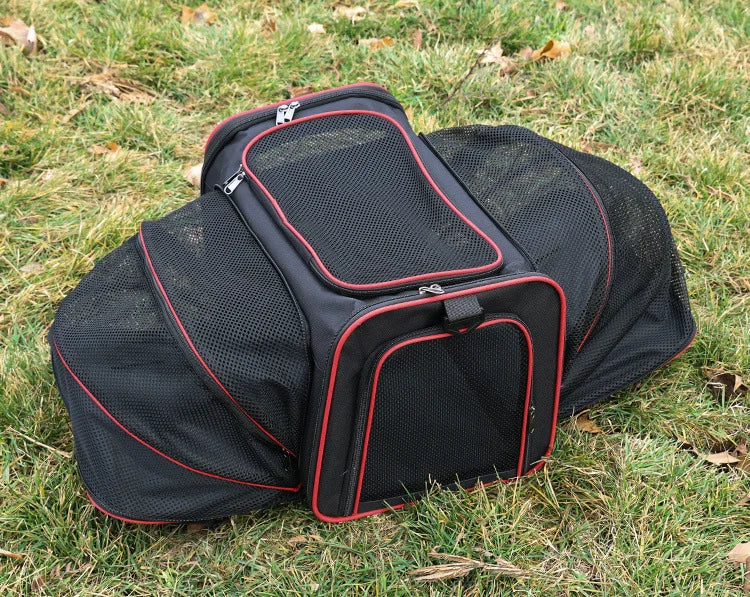 Black expandable mesh pet carrier with red trim, breathable side panels and zippered openings shown outdoors