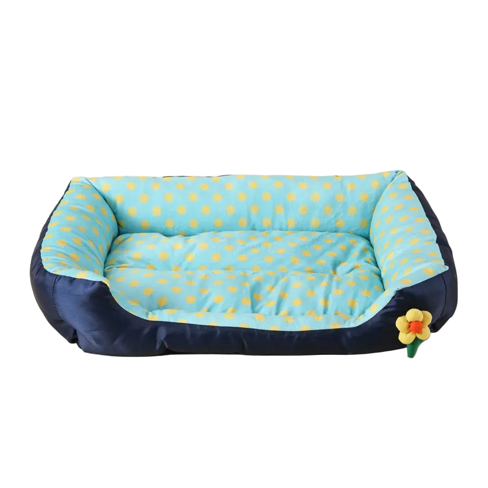 Blue and yellow polka dot bolster dog bed with padded base, raised cushioned sides and decorative flower detail
