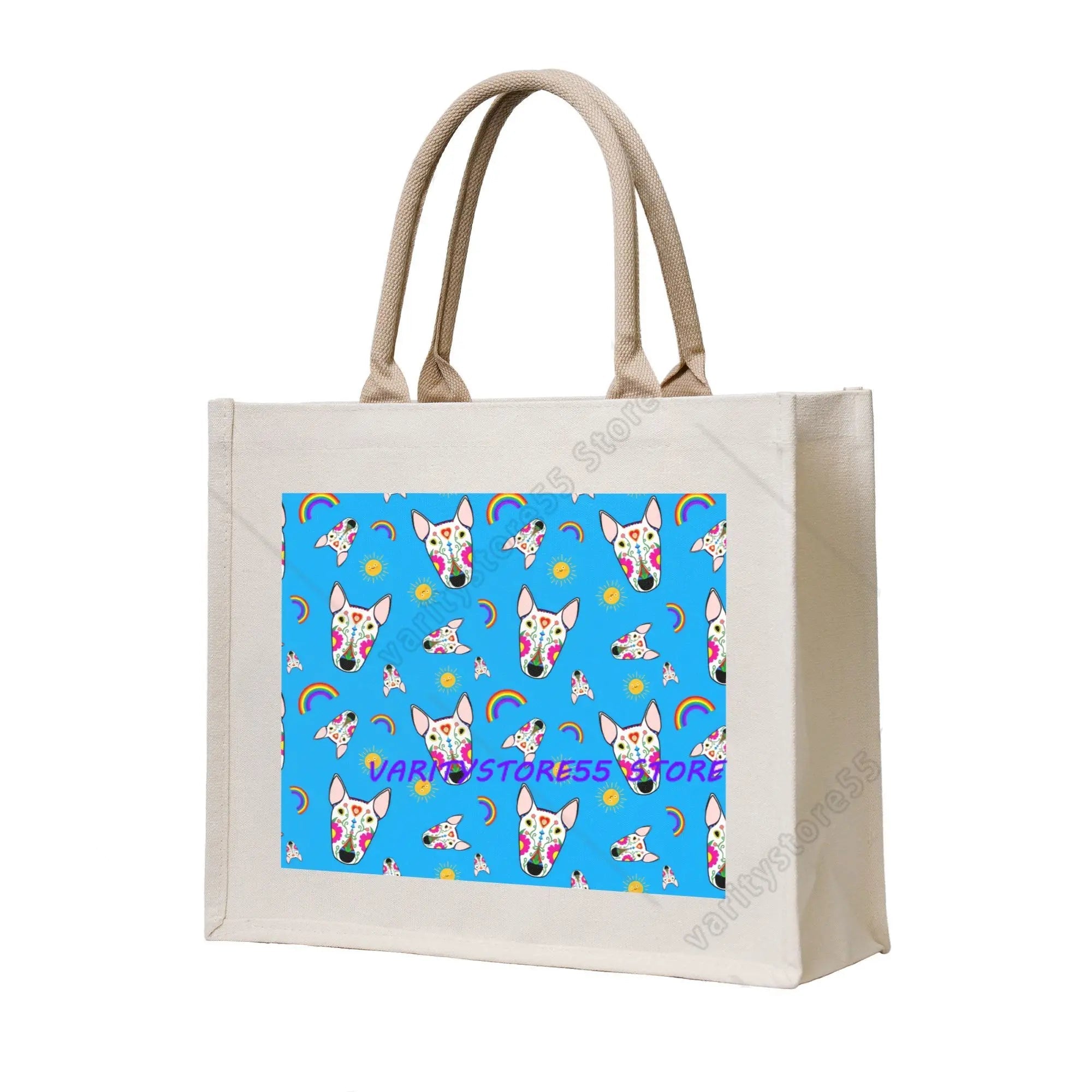 Cream canvas tote bag featuring colourful Bull Terrier faces, rainbows and sun motifs on a blue background