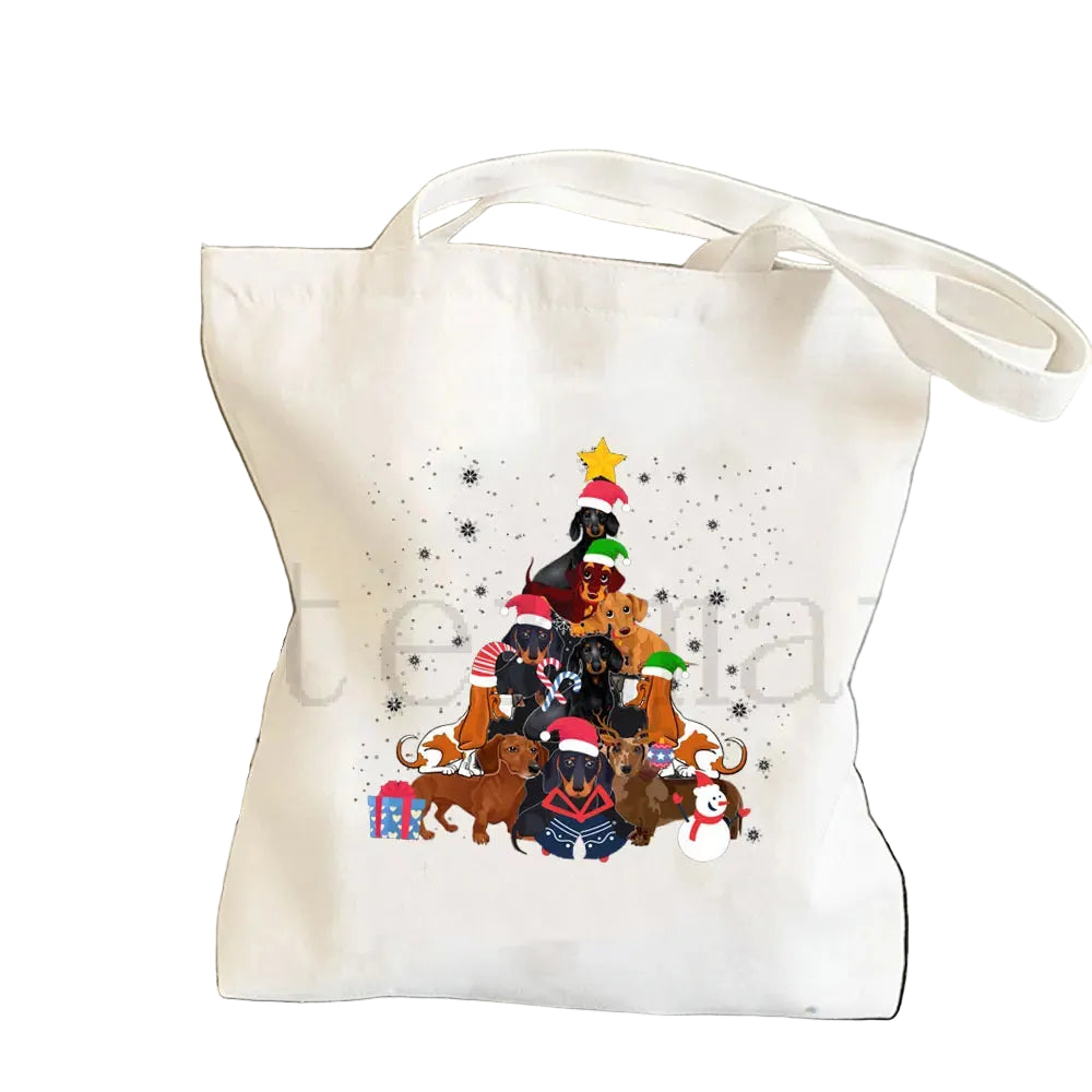 Cream canvas tote bag featuring a Christmas tree made from Dachshunds wearing festive hats, with gifts and a snowman