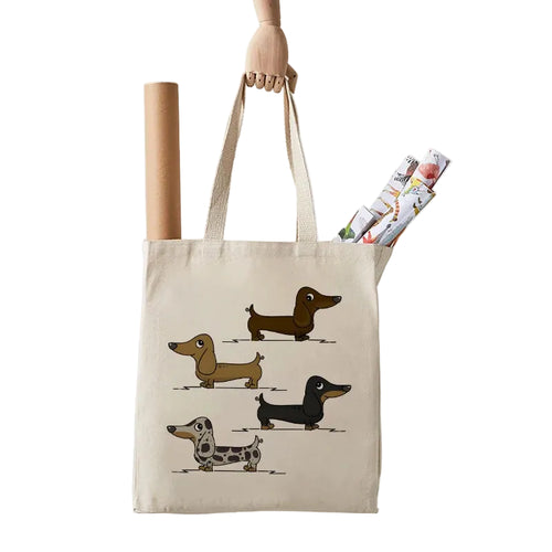 Cream canvas tote bag featuring four illustrated Dachshund dogs in different coat colours