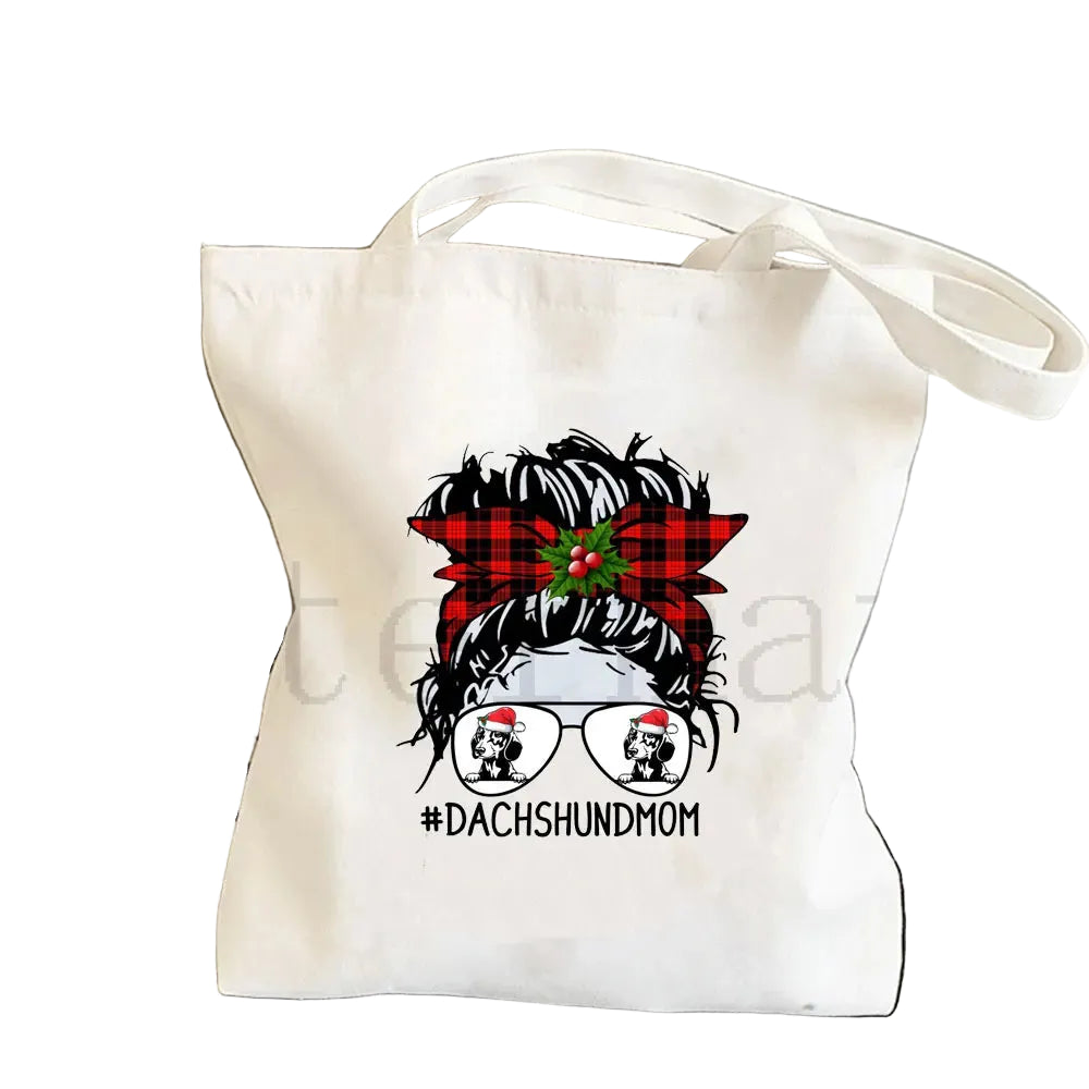 Cream canvas tote bag featuring a Dachshund Mom graphic with a red plaid bow, holly and festive sunglasses