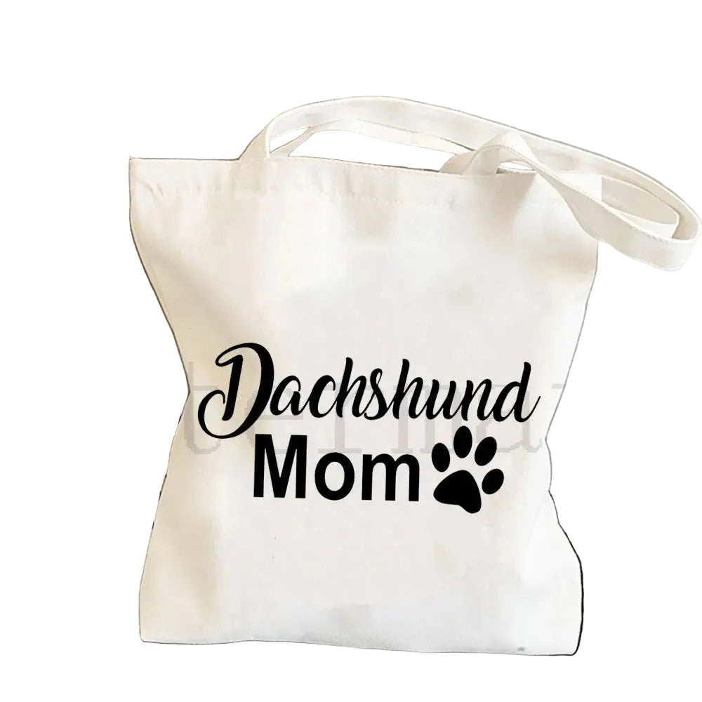 Cream canvas tote bag featuring the words Dachshund Mom with a black paw print graphic
