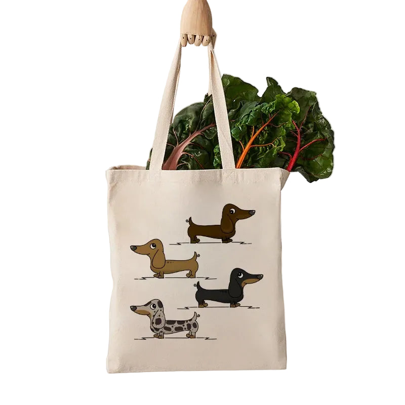 Cream canvas grocery tote bag featuring four illustrated Dachshunds and filled with fresh leafy vegetables