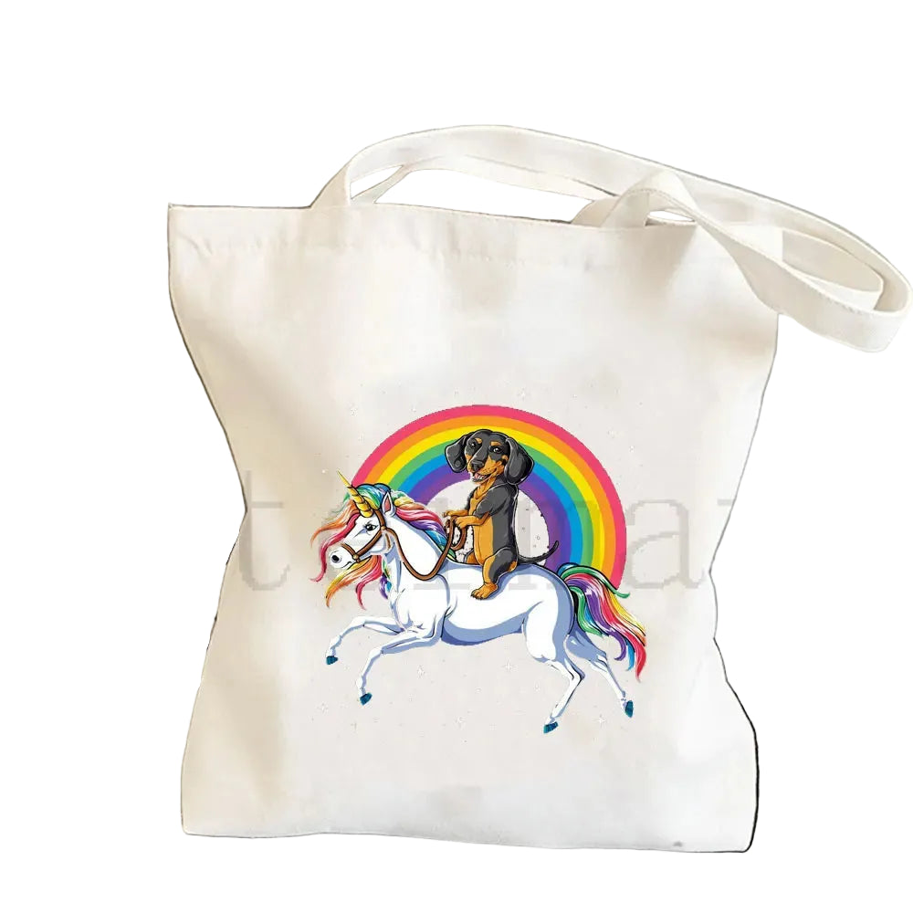 Cream canvas tote bag featuring a Dachshund riding a white unicorn in front of a rainbow