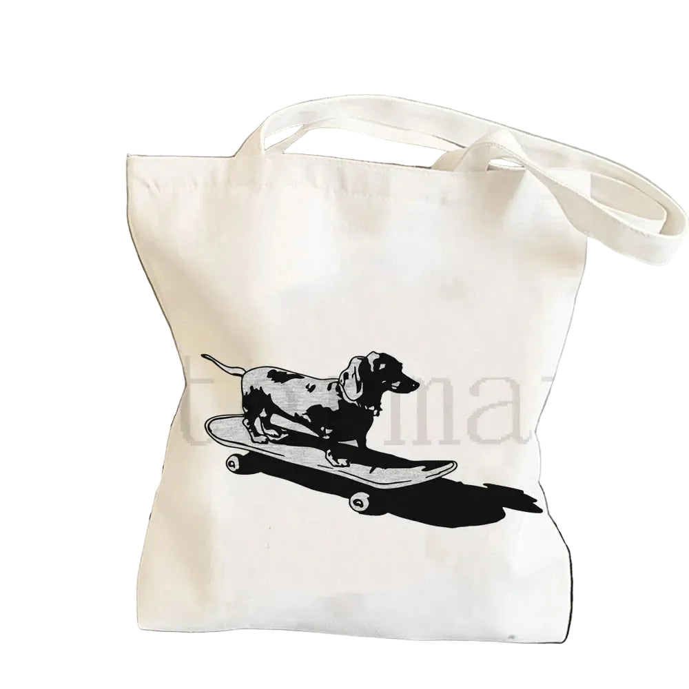 Cream canvas tote bag featuring a black and white Dachshund riding a skateboard