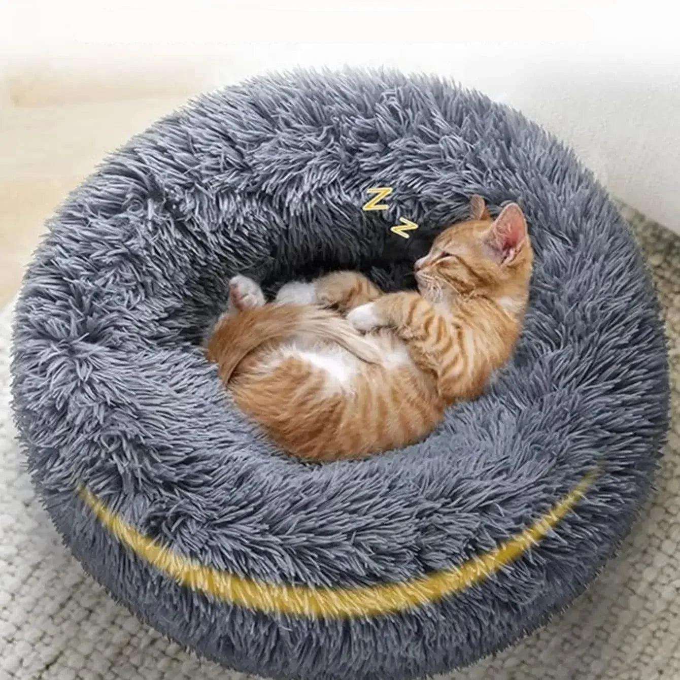 Sleeping kitten curled up in a grey plush donut cat bed with soft faux fur and raised cushioned sides