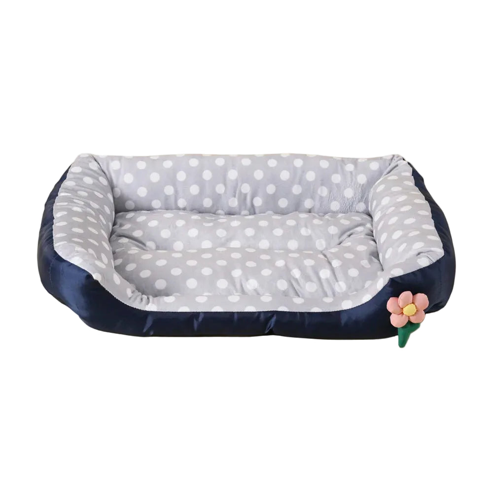 Grey polka dot bolster dog bed with padded base, raised cushioned sides and decorative flower detail