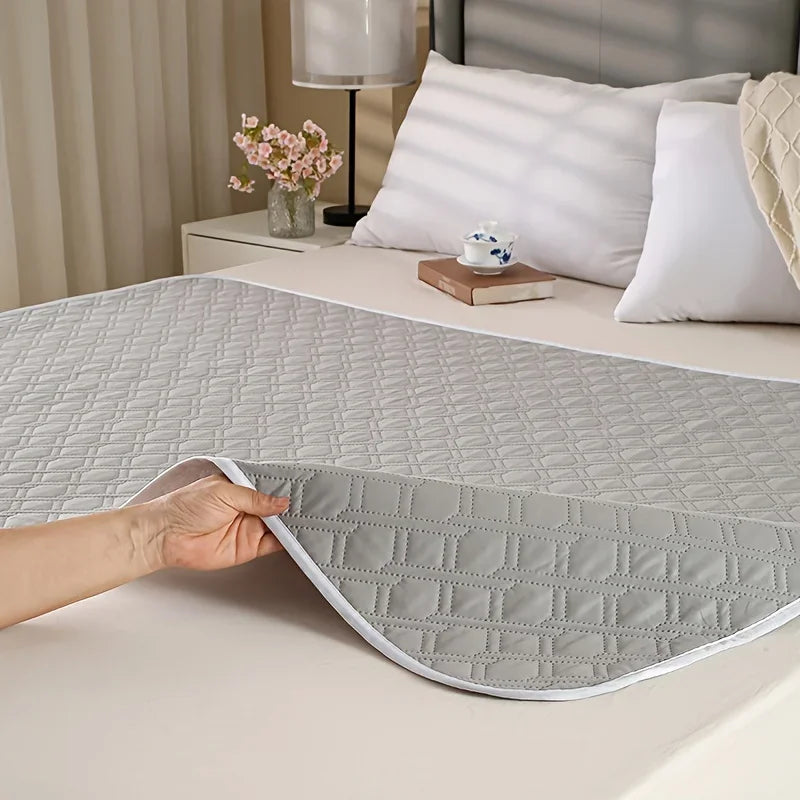 Grey quilted dog bed mat with flexible padded construction and diamond-patterned surface shown on a bed