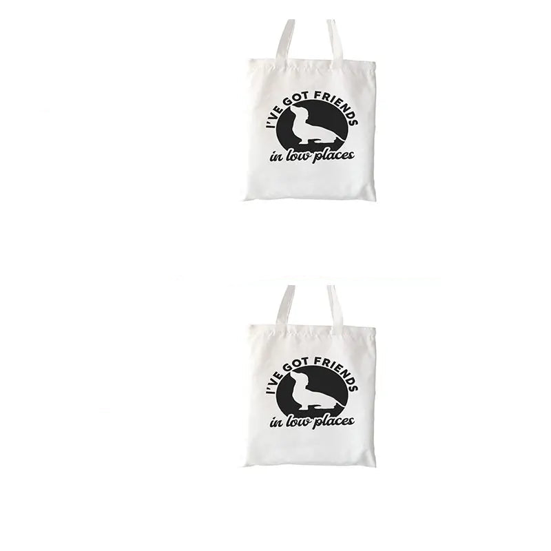 Cream canvas tote bag featuring a Dachshund silhouette with the phrase I've Got Friends in Low Places