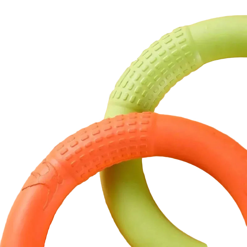 Close-up of orange and green ring-shaped dog chew toys with textured grip sections