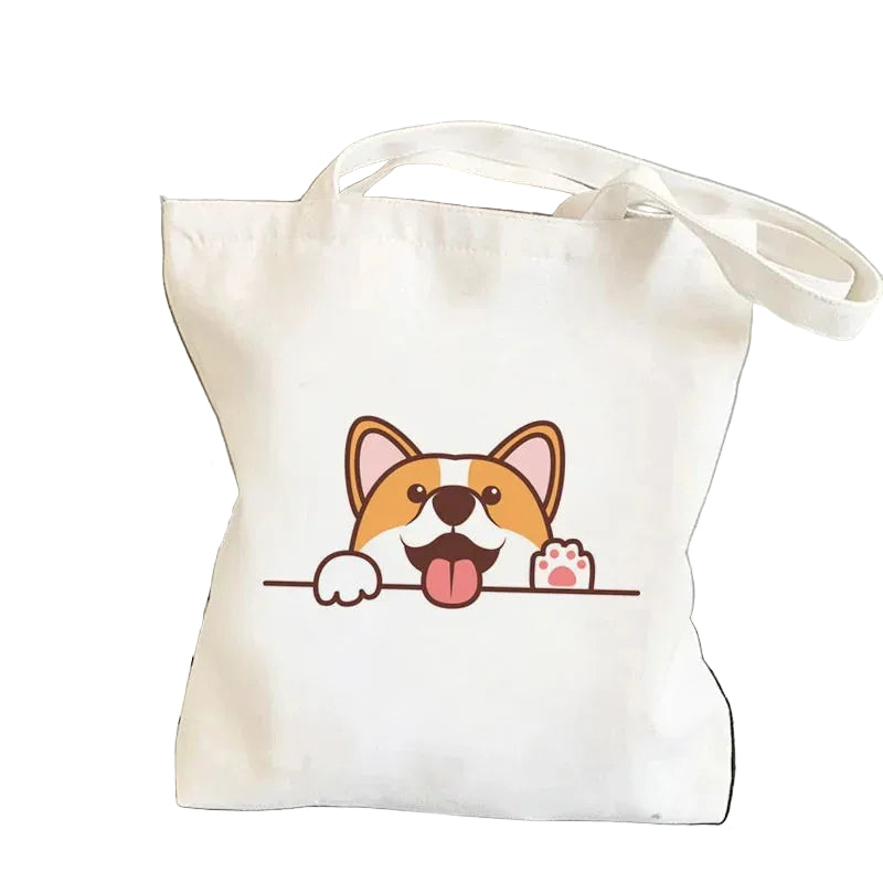 Cream canvas tote bag featuring a happy cartoon Corgi peeking over a line with one paw raised