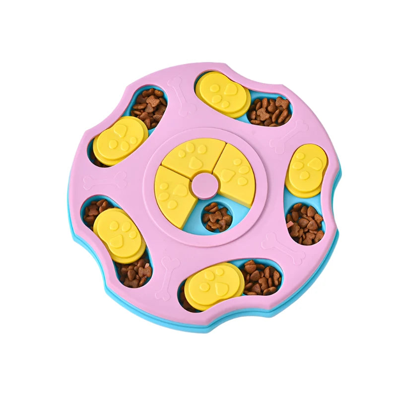 Pink interactive dog puzzle feeder with yellow sliding covers and compartments filled with dry dog food