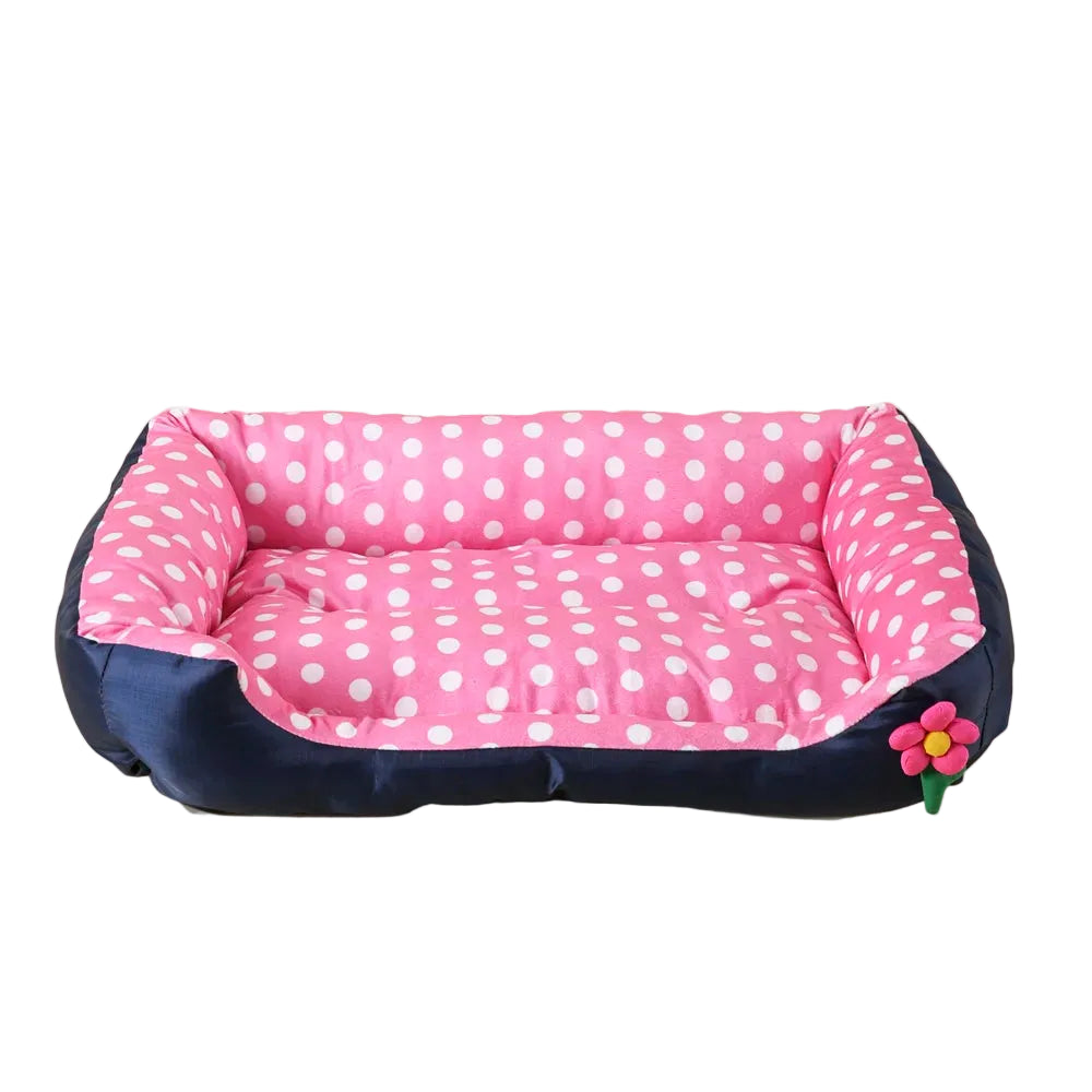 Pink polka dot bolster dog bed with padded base, raised cushioned sides and decorative flower detail