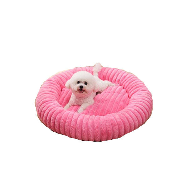 Small white dog resting in a pink round ribbed dog bed with raised cushioned sides