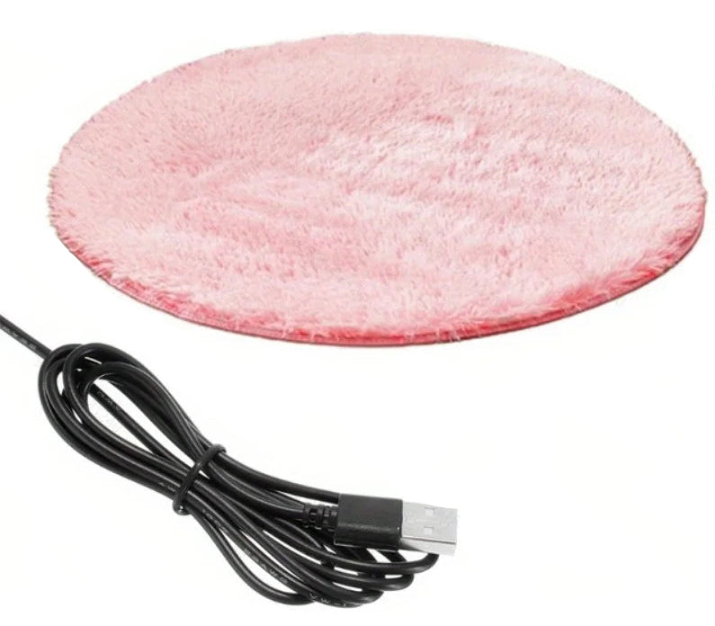 Golden Retriever puppy and orange tabby kitten resting together on a round electric heated pet mat