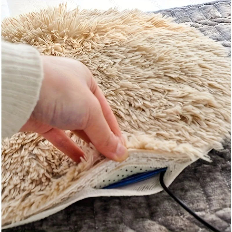 Close-up of a plush electric heated pet mat with removable cover lifted to show the inner heating pad and power cord
