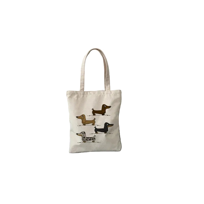 Small cream canvas tote bag featuring four illustrated Dachshund dogs in different coat colours
