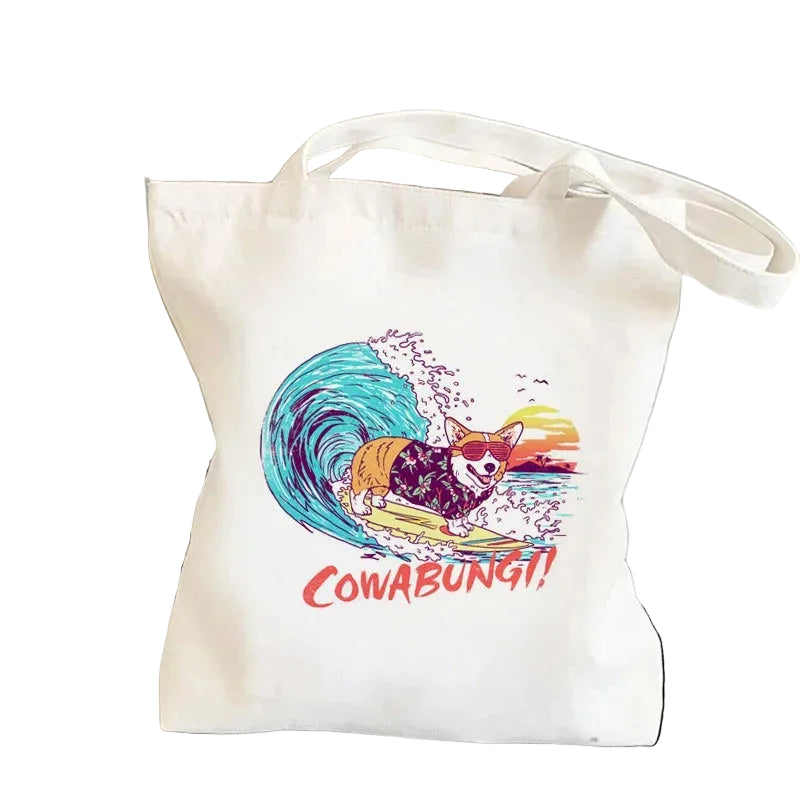 Cream canvas tote bag featuring a Corgi surfing a blue wave with the word Cowabungi